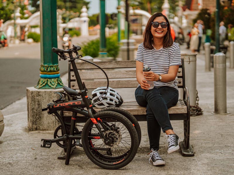 A rider sits next to her black Polygon Urbano 3 on the city bench A rider sits next to her black Polygon Urbano 3 on the city bench