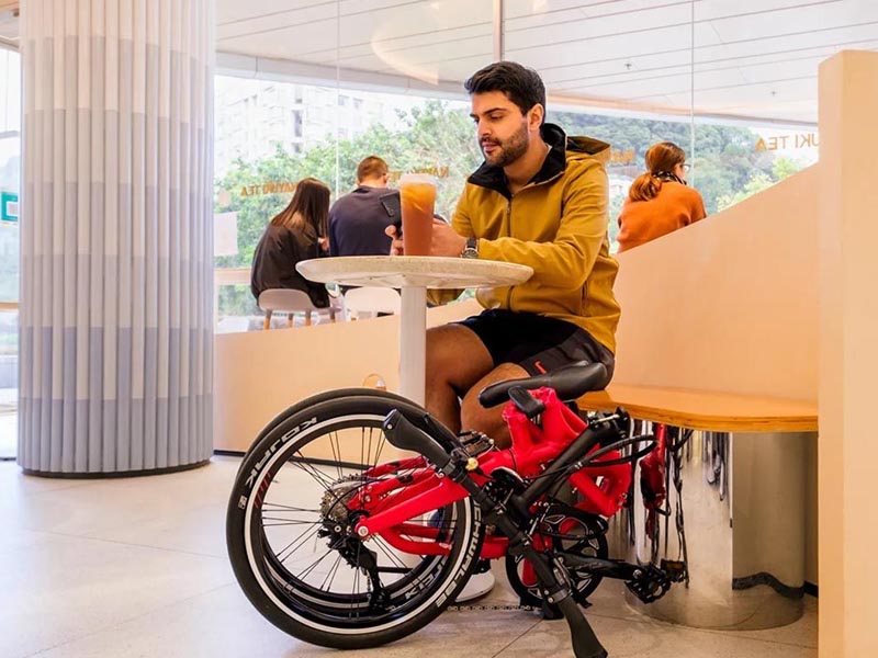 A cyclist brings his folded red Tern BYB P10 inside the cafe A cyclist brings his folded red Tern BYB P10 inside the cafe
