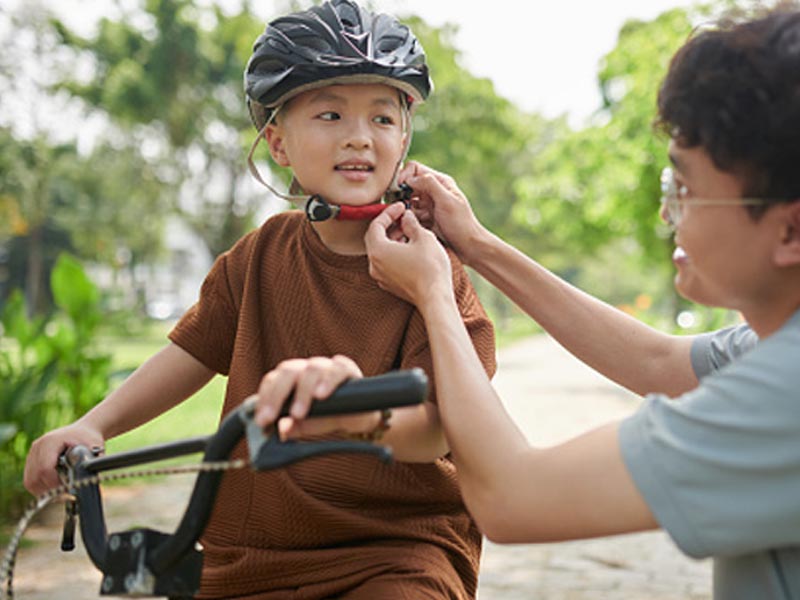Seorang ayah memasangkan helm ke anaknya Seorang ayah memasangkan helm ke anaknya