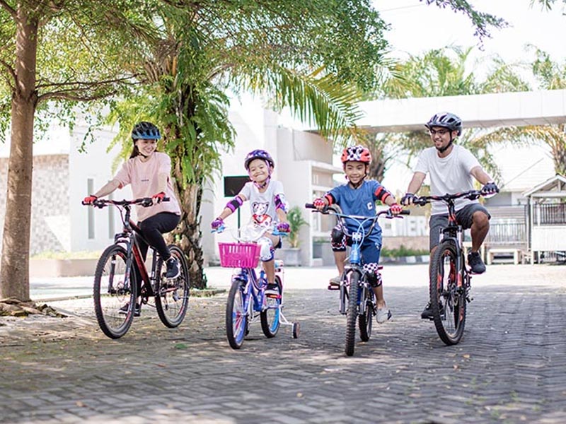 Keluarga kecil sedang bersepeda santai bersama-sama menggunakan helm untuk keamanan ekstra Keluarga kecil sedang bersepeda santai bersama-sama menggunakan helm untuk keamanan ekstra