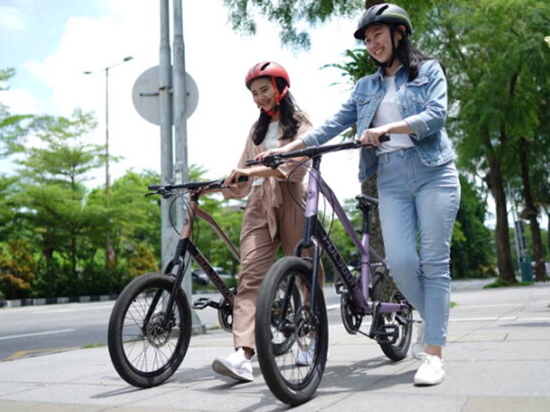 Dua pesepeda sedang berjalan menuntun sepeda gili velo sambil mengobrol santai Dua pesepeda sedang berjalan menuntun sepeda gili velo sambil mengobrol santai