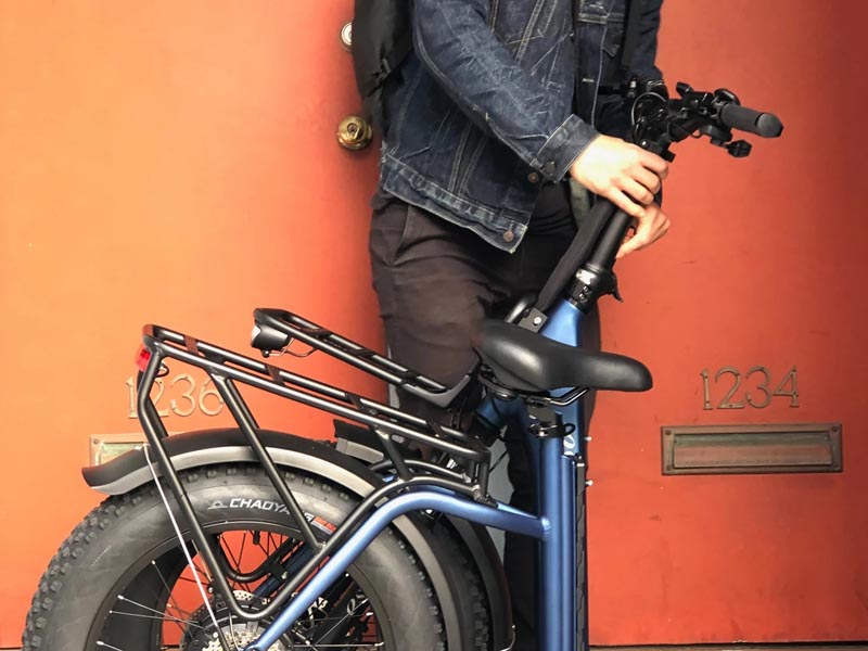 Foldable bike owner takes his blue bike in folded state Foldable bike owner takes his blue bike in folded state