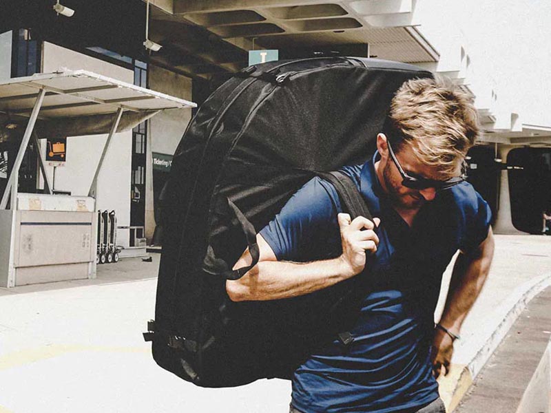 A man carefully carrying his travel case with a foldable bike inside A man carefully carrying his travel case with a foldable bike inside