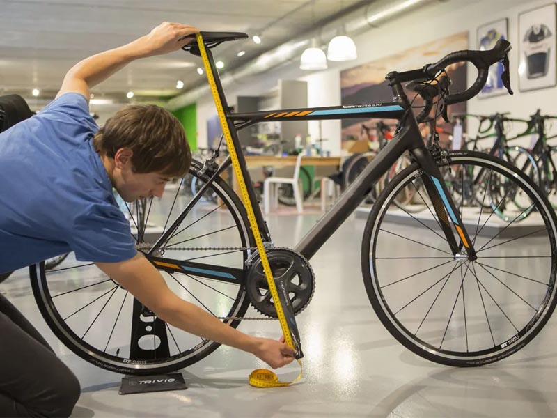 A cyclist measure his saddle height with gauge tape A cyclist measure his saddle height with gauge tape