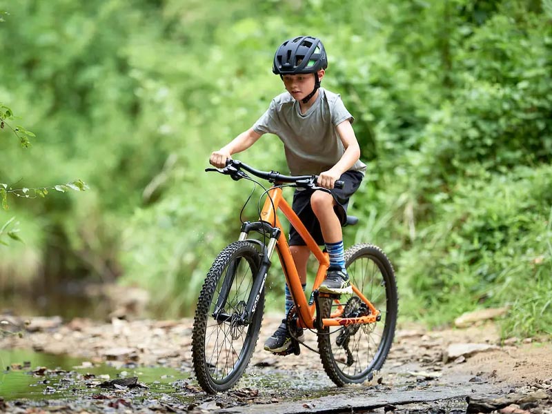 On the mountain, a young boy use his kids MTB to learn mountain biking On the mountain, a young boy use his kids MTB to learn mountain biking