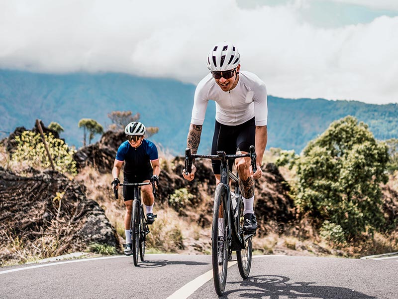 Two cyclists practice road biking on the uphill track Two cyclists practice road biking on the uphill track