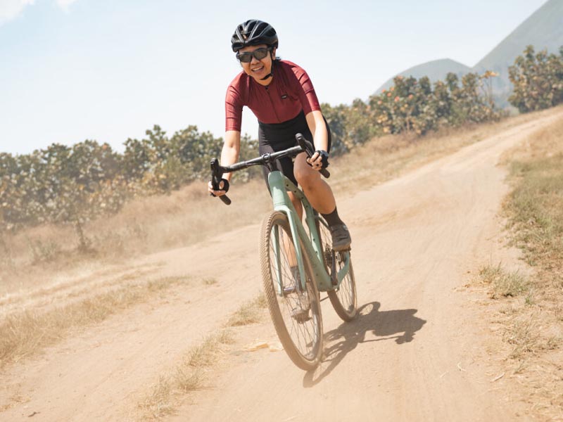 A cyclist with her essential gear pedals on the gravel track A cyclist with her essential gear pedals on the gravel track