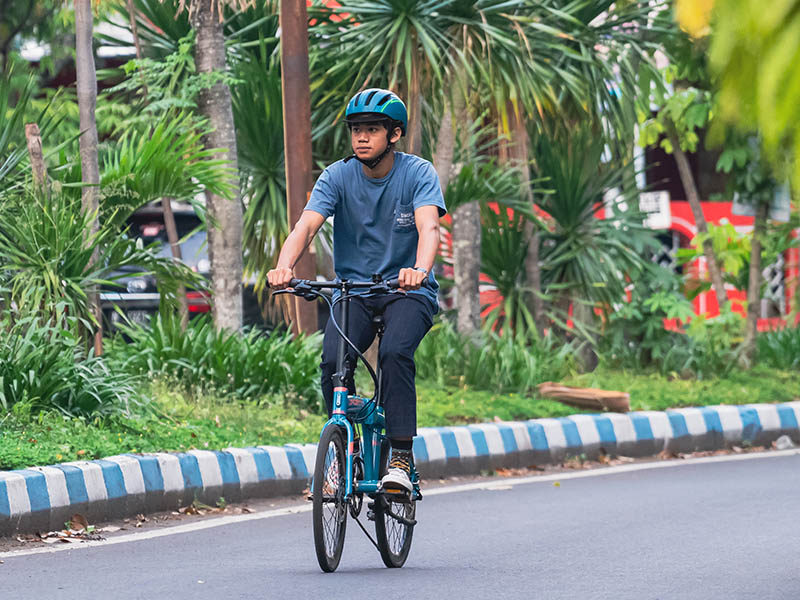 Seorang pesepeda berkendara dengan aman menggunakan helm Seorang pesepeda berkendara dengan aman menggunakan helm
