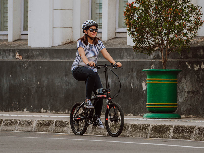 A women strolling around the city with her folding bike A women strolling around the city with her folding bike