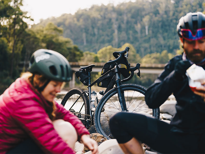Pesepeda Gravel beristirahat dengan sepeda di sampingnya Pesepeda Gravel beristirahat dengan sepeda di sampingnya