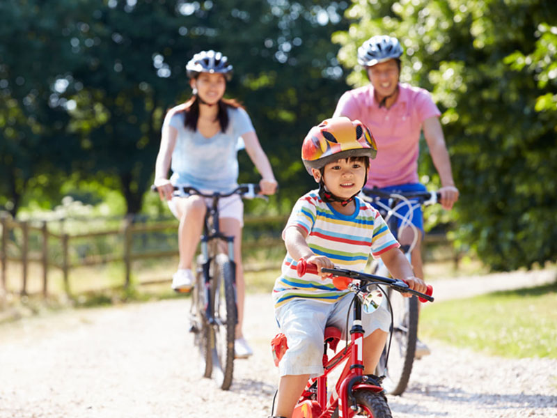 Seorang anak menikmati waktu bersepeda bersama orang tuanya Seorang anak menikmati waktu bersepeda bersama orang tuanya