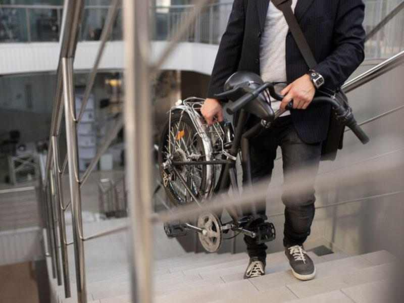 A cyclist brings his foldable bike upstairs A cyclist brings his foldable bike upstairs