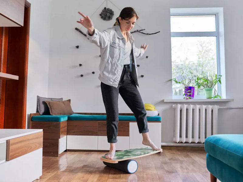 Seorang wanita berlatih keseimbangan dengan balance board Seorang wanita berlatih keseimbangan dengan balance board