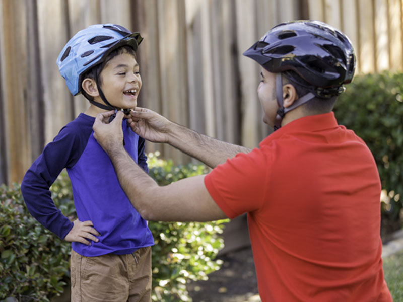 Orang tua memasangkan helm sepeda ke anaknya Orang tua memasangkan helm sepeda ke anaknya