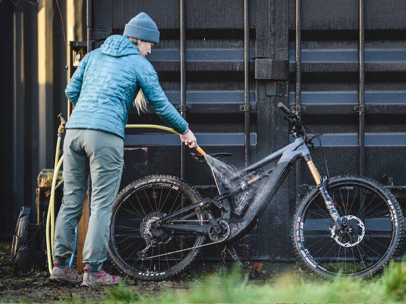 Cyclist mencuci sepeda gunung setelah bersepeda di waktu hujan Cyclist mencuci sepeda gunung setelah bersepeda di waktu hujan